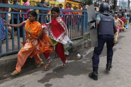 Police officer raises baton as garment workers run