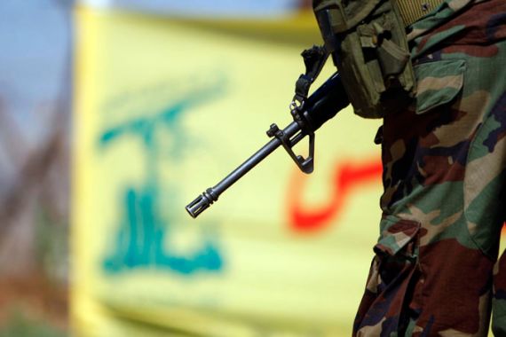 Lebanese army soldier in front of Hezbollah flag