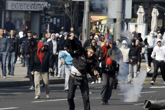 An anti-gay protester throws a stone towards riot policemen during clashes in Belgrade