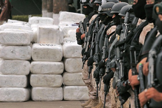 Soldiers stand guard next to narcotics wrapped in silver packages in Tijuana