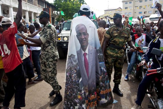 A supporter of Guinea''s presidential candidate Cellou Dalein Diallo walks past gendarmes at a rally in Conakry