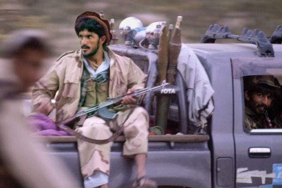 Armed Afghan militia members ride in a truck