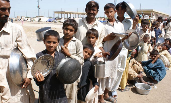 People displaced from flooded areas wait to get donated food in Pakistan