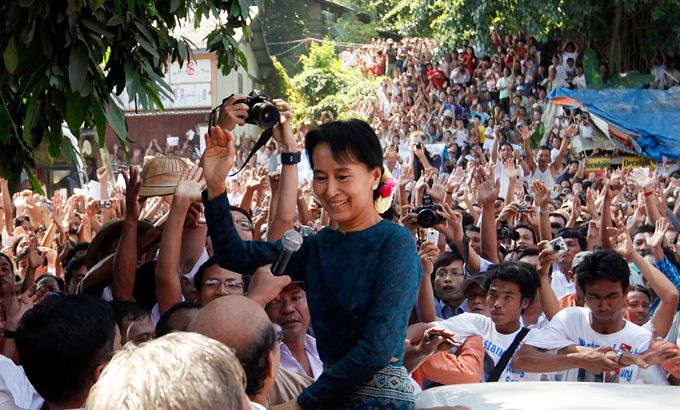 Aung San Suu Kyi waves to supporters outside headquarters of NLD