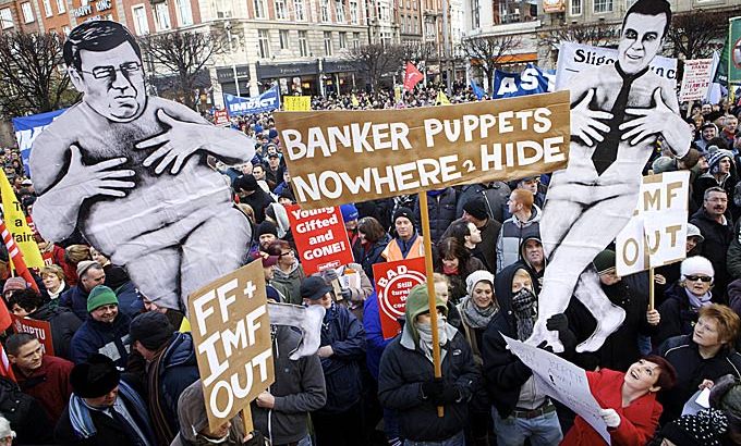 Placards depicting a naked Irish Prime Minister Brian Cowen and Minister for finance, Brian Lenihane are held as over 50,000 people march to the General Post Office on O'' Connell Street in Dublin on 27 November 2010.