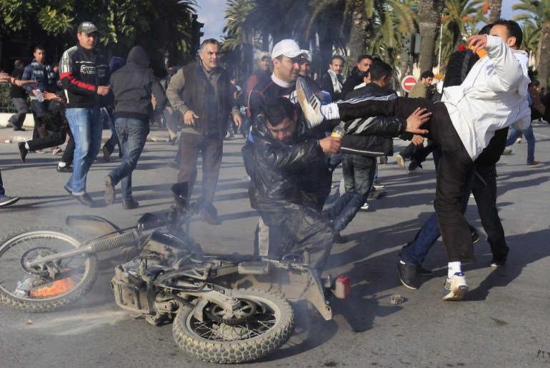 A protester hits a policeman during clashes with riot police in downtown of the capital Tunis