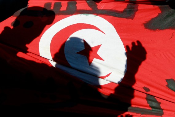 Silhouettes of people are seen on the Tunisian flag during a peaceful demonstration in the Ettadamen suburb of Tunis