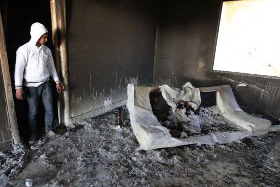A Tunisian man looks at a burnt sofa at the empty and ransacked home of Kaif Ben Ali, nephew of former President