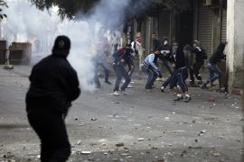 A riot police officer fires tear gas at protesters during clashes in Belcourd district of the capital Algiers