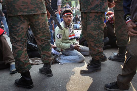 An Egyptian peers through the legs of troops in Tahrir Square
