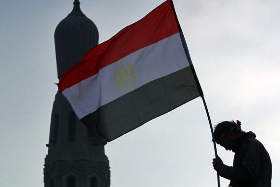 An opposition supporter holds an Egyptian flag atop a lamp post near a mosque in Tahrir Square in Cairo