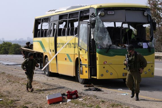 Israeli soldiers walk next to a damaged bus after it was hit by an anti-tank missile fired from the Gaza Strip into southern Israel, on the road between kibbutz Nahal Oz and kibbutz Sa''ad April 7, 2011. An anti-tank missile fired from Gaza hit an Israeli school bus on Thursday, wounding several people, and Israeli forces retaliated by shelling the territory, killing a 50-year-old man, Palestinian medics said. REUTERS/Shalom Gaziel (ISRAEL - Tags: POLITICS CIVIL UNREST)