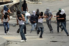 Palestinian youths hurl stones towards Israeli troops inthe Eeast Jerusalem neighborhood of Silwan