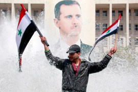 syrian protester with Bashar al assad backdrop