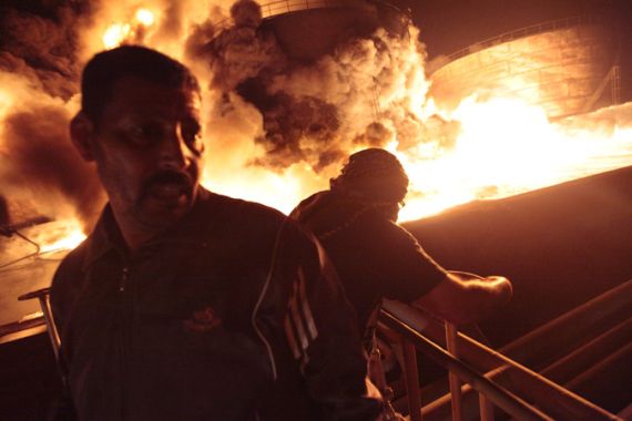 Libyan men watch as the main fuel depot in Libya''s third largest city Misrata burns