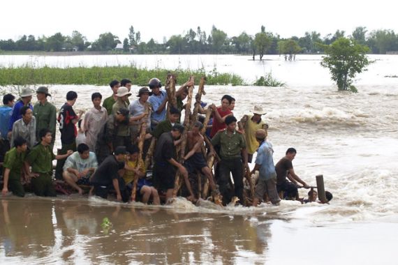 Rescuers stand on a broken dyke of the Mekong river in An Giang province September 28, 2011.
