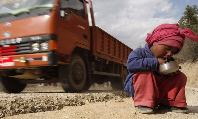 A Nepalese child sits on the side of the road