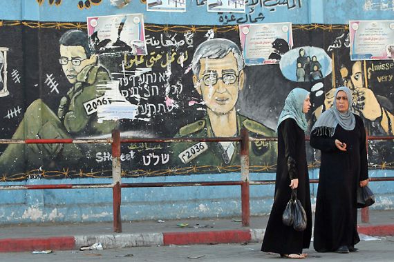 Palestinian women walk past a mural depicting captured Israeli soldier Gilad Shalit