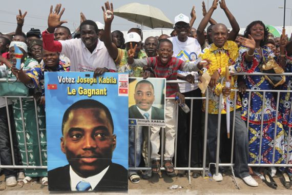 Congolese spectators holding portraits of President Joseph Kabila cheer as they watch the military parade