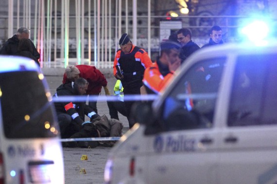 Police officers and experts surround a dead body at the Place Saint Lambert square where a man threw explosives in the city center belof the Belgian city of Liege December 13, 2011.