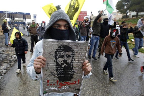 A Palestinian demonstrator holds a placard depicting prisoner Khader Adnan