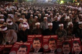 Supporters of Mohamed Mursi, head of the Muslim Brotherhood''s political party and the Brotherhood''s presidential candidate, hold posters of Mursi during his last campaign rally in airo