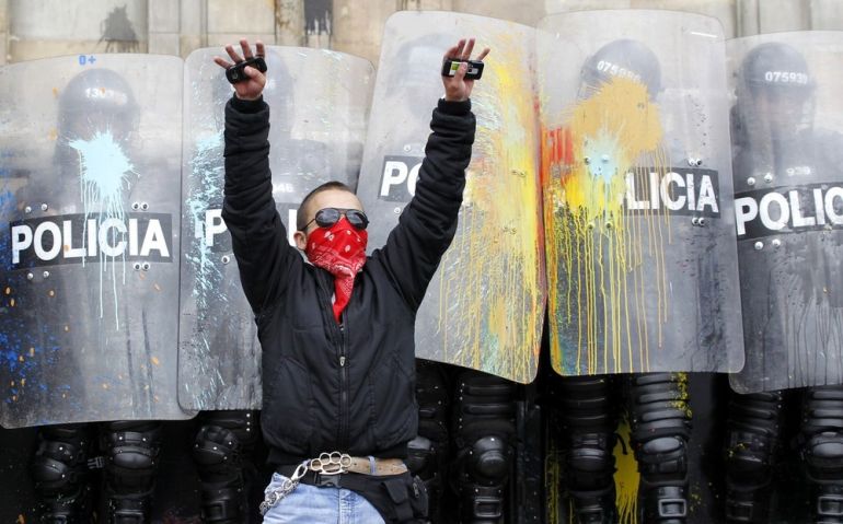 A student demonstrator tries to stop fellow protesters from throwing stones and paintballs at riot policemen during clashes on May Day in Bogota