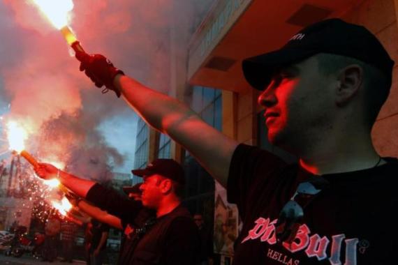 Members of the Greek extreme right Golden Dawn party hold red flares outside the town hall of Perama town