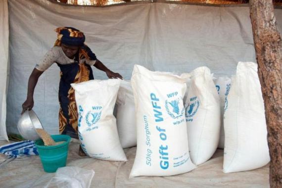 Aid workers prepare rations of sorghum t