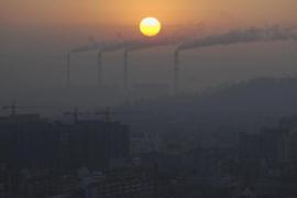 Smoke billows from the chimneys of a power plant during sunrise in Jiaxing