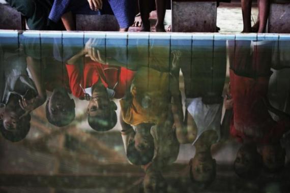 Myanmar Rohingya children are reflected in a fountain outside a mosque in the village of Gollyadeil north of the town of Sittwe
