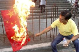 An activist burns a flag of China during a protest to demand that the Chinese government pull out from the Scarborough Shoal during a rally in front of the Chinese consular office in Makati''s financial district of Manila