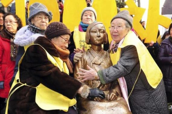 Former South Korean comfort women pose with the Peace Statue symbolizing a wartime sex slave at the 1,000th weekly anti-Japan rally in front of the Japanese embassy in Seoul