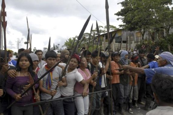 Ecuadorean Achuar Indians gathering on a road raise their weapons during a protest in Puyo