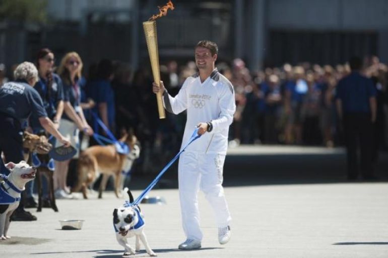 Former England striker Michael Owen carries the Olympic Torch through Battersea dogs home with a Staffordshire Bull Terrier called Rory in London