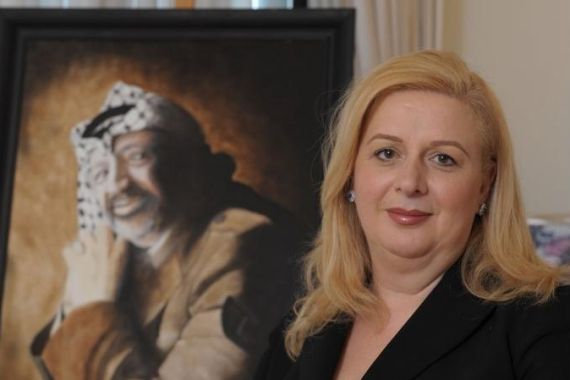 Suha Arafat poses in front of a portrait