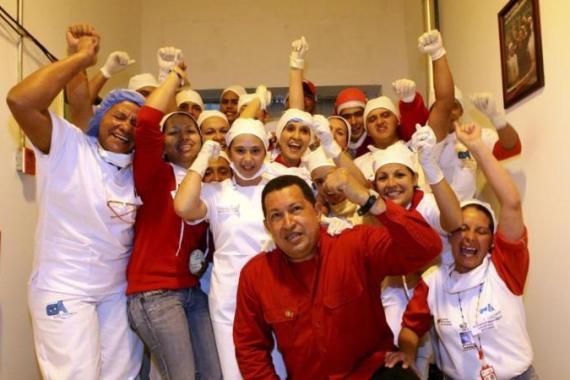 Venezuela''s President Hugo Chavez poses with workers during a visit to a socialist factory of milk products in the state of Tachira