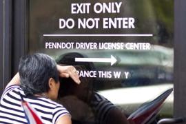 A woman peers in through a glass door at a Pennsylvania Department of Transportation office in Philadelphia to get a voter ID card