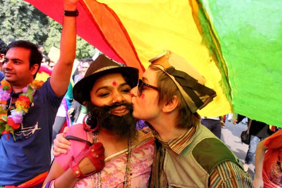 Marchers on Delhi''s Gay Pride Parade kiss under a rainbow flag [Showkat Shafi/Al Jazeera]