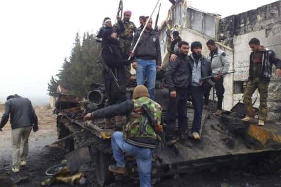 Free Syrian Army fighters from Al-Farooq battalion celebrate atop damaged tanks after the fighters said they fought and defeated government troops in Halfaya