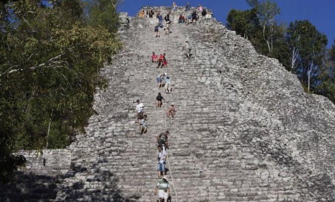 Tourists climb the Maya pyramid of Nohoch Mul at the archaeological site of Coba