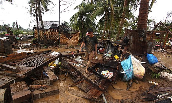 Residents walk amongst their destroyed houses after Typhoon Bopha hit