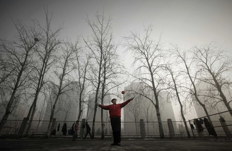 A resident plays with a diabolo in a park during a heavily hazy winter day in Beijing