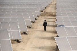 A man walks through solar panels at a solar power plant under construction in Aksu