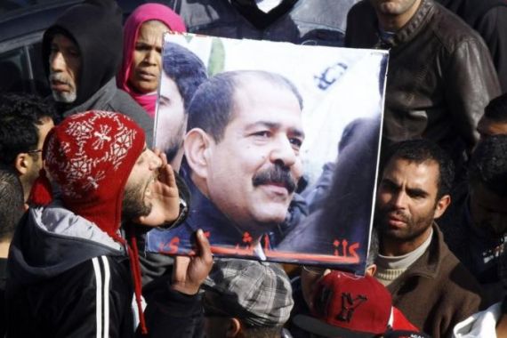 Tunisians hold a placard with an image of the late secular opposition leader Chokri Belaid during his funeral procession in Tunis