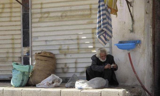 A man sits beside a graffiti in Azzaz