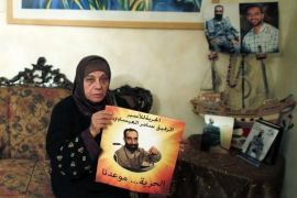 Layla al-Issawi holds a placard depicting her son Samer, held in an Israeli prison, at her home in East Jerusalem