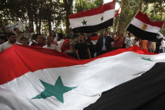 Anti-Syrian government demonstrators who are Egyptians and Syrians shake the Syrian flag while chanting anti-Syrian government slogans as they protest in front of the Syrian embassy in Cairo
