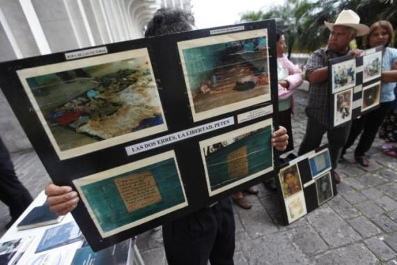 Relatives of Guatemalan farmers murdered in 1982 hold posters during the start of the trial of former soldiers Manuel Popsun, Reyes Gualip and Carlos Carias outside the justice courts in Guatemala City