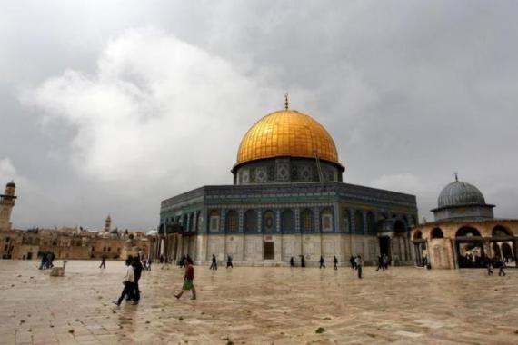 People walk past the Dome of the Rock at